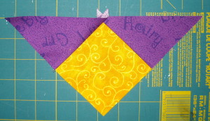 The purple triangles sewn to the yellow square.