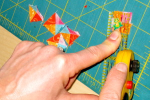 Trimming off the dog ears on the ½″ quarter square triangles.