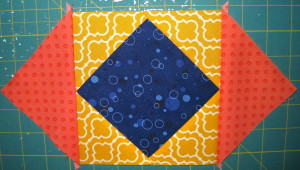 Sew 2 red-orange triangles to opposite sides