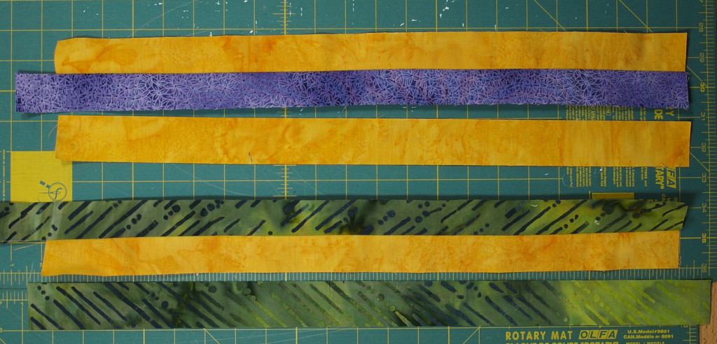 An orange strip sewn to a purple and a green strip from each set of strips