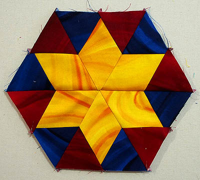 Six pointed yellow star surrounded by red and blue diamonds in a hexagon shape