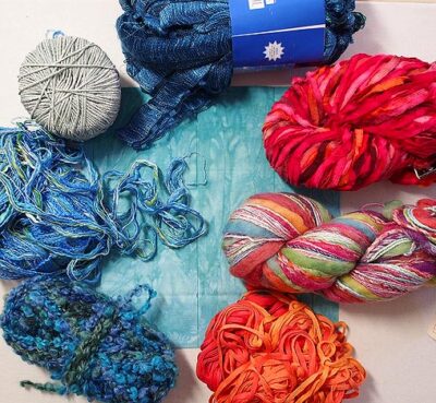 Variety of yarns and a piece of teal fabric