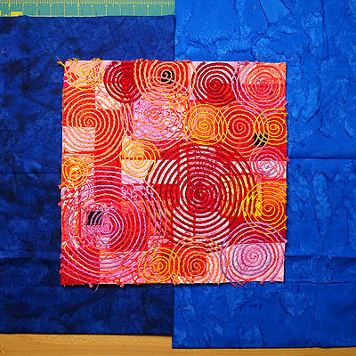 Two blue fabrics with a multicoloured square on top