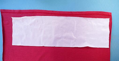 White interfacing lying on red knit fabric