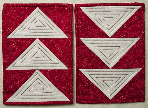 Two red and white flying geese mug rugs