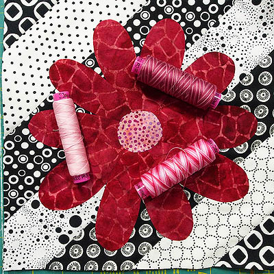 Three spools of pink thread on the red flower