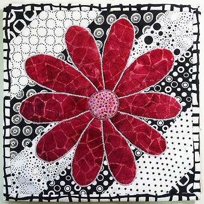 Completed black and white mug rug with a red flower