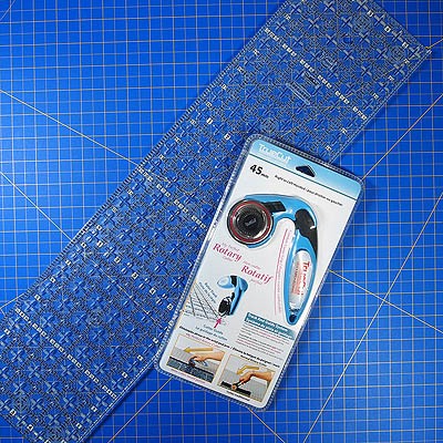 rotary cutter and ruler on a blue cutting mat