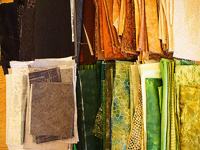A pile of brown, gold, black, green and grey fabrics