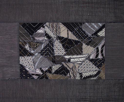 A variety of black and grey fabrics in triangles to create the mountains framed in dark grey