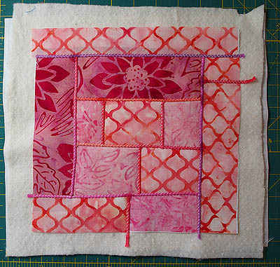 Pink, orange and red fabrics with yarn in vertical and horizontal lines