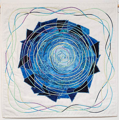Multiple blue fabrics in a circle with yarn around the white outside