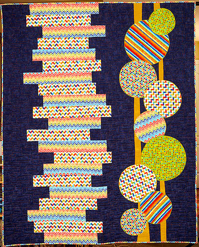 blue quilt with white and multi-coloured rectangles and circles