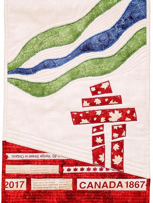 appliqué block in red, cream, green and blue of an Inukshuk and the northern lights