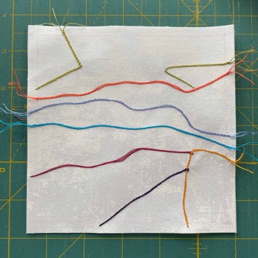 lines stitched in multiple colours on white fabric