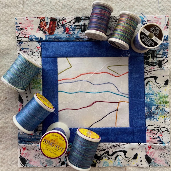 7 spools of thread on a quilt block