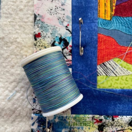 multi coloured thread spool on a quilt border