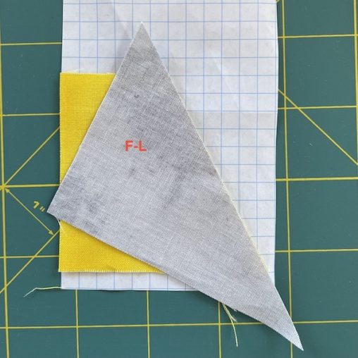 grey triangle fabric on top of yellow fabric on graph paper