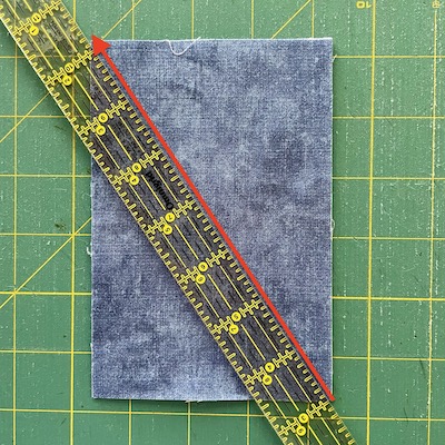 red arrow and ruler placed on a diagonal on a blue piece of fabric
