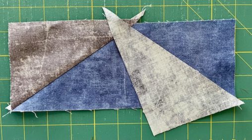 grey triangle facing down on blue fabric and sewn in place