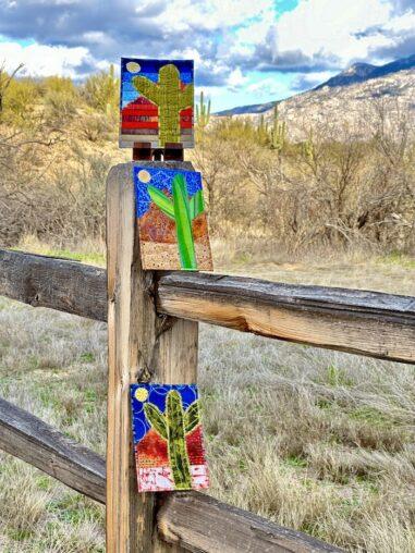 a fence with 3 colourful postcards