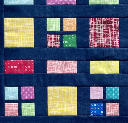 colourful fabric squares and rectangles between navy blue sashing fabric